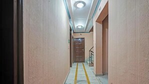 A hallway with a wooden door at the end, a handrail on the right, and a yellow line on the floor. - Fabhotel Iconic Residency (New Delhi)