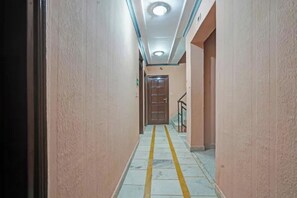 Un passadís amb una porta de fusta al final, una barana a la dreta i una línia groga al terra.