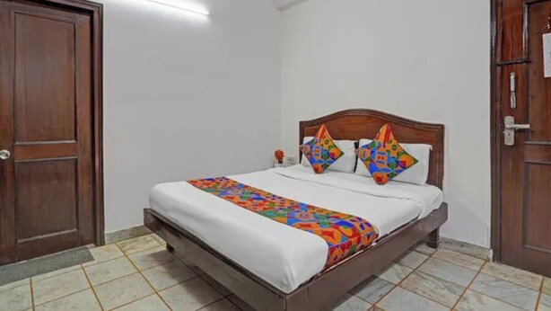 A room with a single bed, a wooden door, and a tiled floor. - Fabhotel Iconic Residency (New Delhi)
