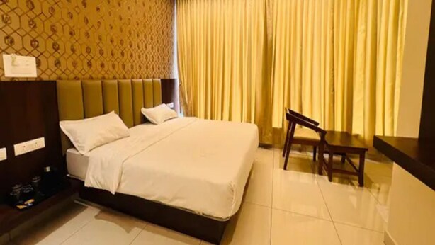 Quarto de hotel com uma cama, uma cadeira, uma escrivaninha e parede com padrão.