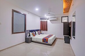 A modern bedroom with a bed, bedside tables, a ceiling fan, an air conditioning unit, and a large window with curtains. - FabHotel Agm (Ahmedabad)