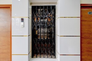 Un ascensor con una puerta metálica, un panel de control y una puerta de madera con un número.