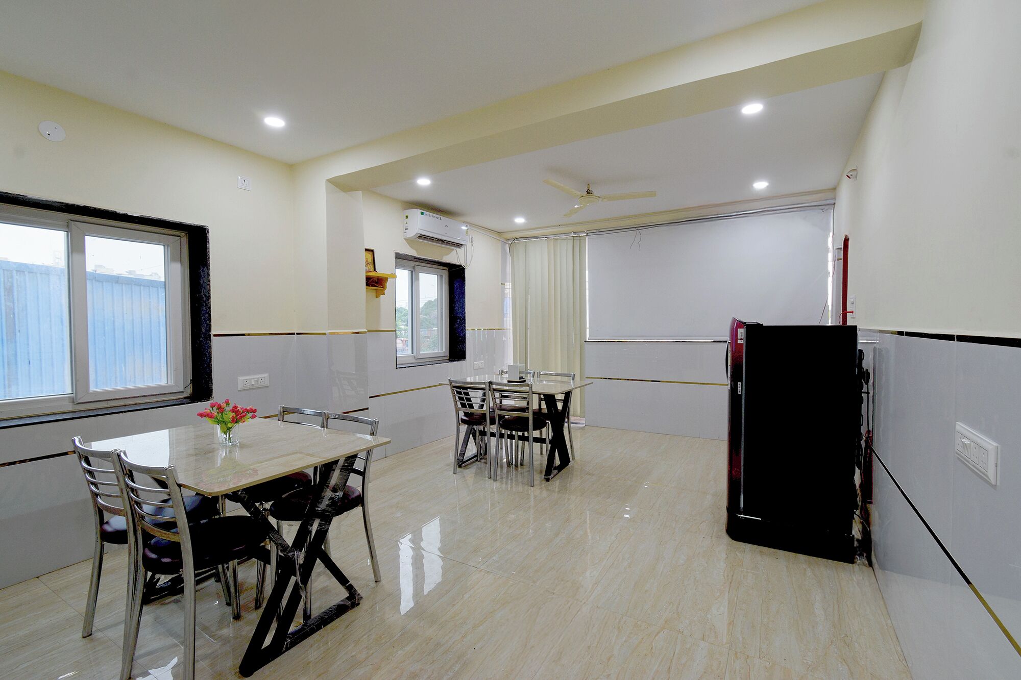 Una cocina moderna con una mesa de comedor, sillas, un refrigerador y una ventana.