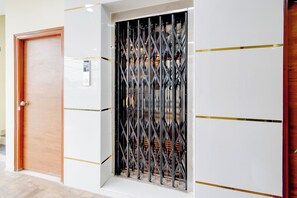 Una puerta con un cerrojo metálico, una pared con un panel blanco y un marco de madera.