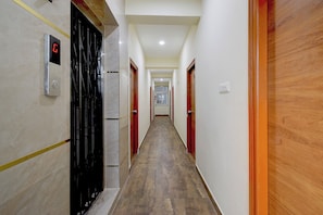 A corridor with doors on both sides, a digital clock, and a window at the end. - Fabhotel Swagath Inn (Hyderabad)