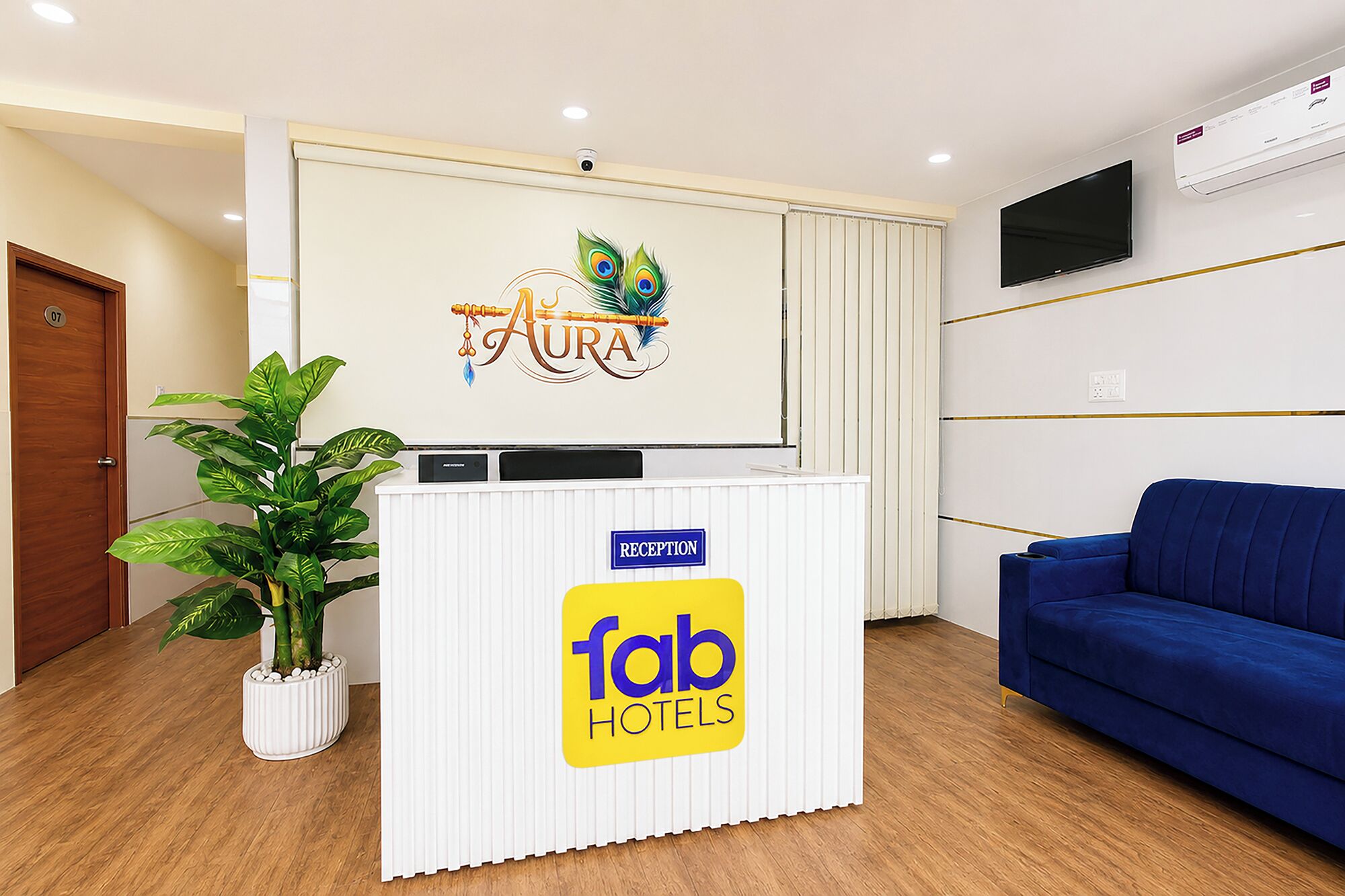 Un mostrador de recepción con un logotipo, una señalización de recepción, un televisor y un sofá azul.
