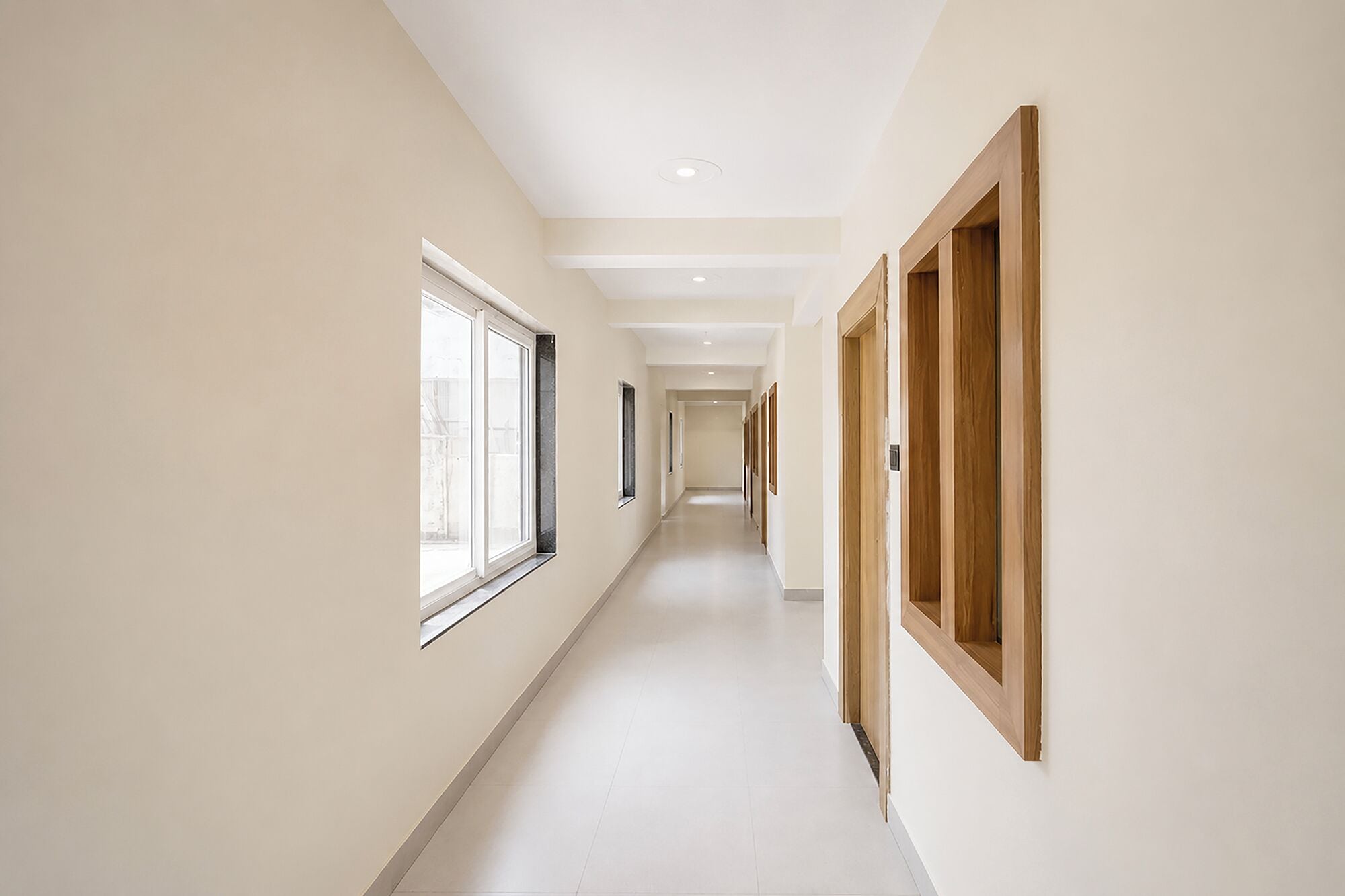 Un pasillo con una ventana a la izquierda y una puerta de madera a la derecha.
