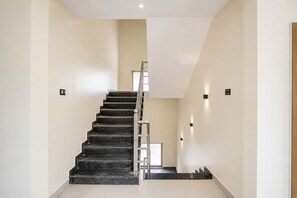 A modern interior with a staircase leading to a higher floor, light-colored walls, and minimalistic design. - FabHotel Ramanjnaeya (Faizabad)