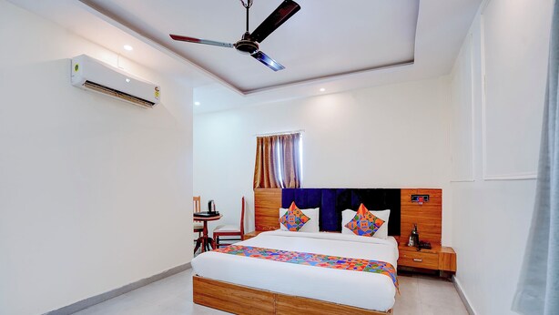 Una habitación de hotel con una cama, una mesita de noche, un ventilador de techo y un equipo de aire acondicionado.