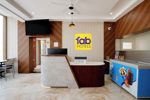 A hotel reception area with a modern design, including a marble counter, a ceiling fan, and a sign for 'fab hotels'. - Fabhotel Ramanjnaeya (Faizabad)