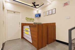 Een receptiebalie met een bordje waarop 'Dhaya Grand Inn' en 'Fab Hotels' staat.