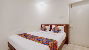 A single bed with a colorful geometric-patterned bedspread, a wooden headboard, and two decorative pillows.