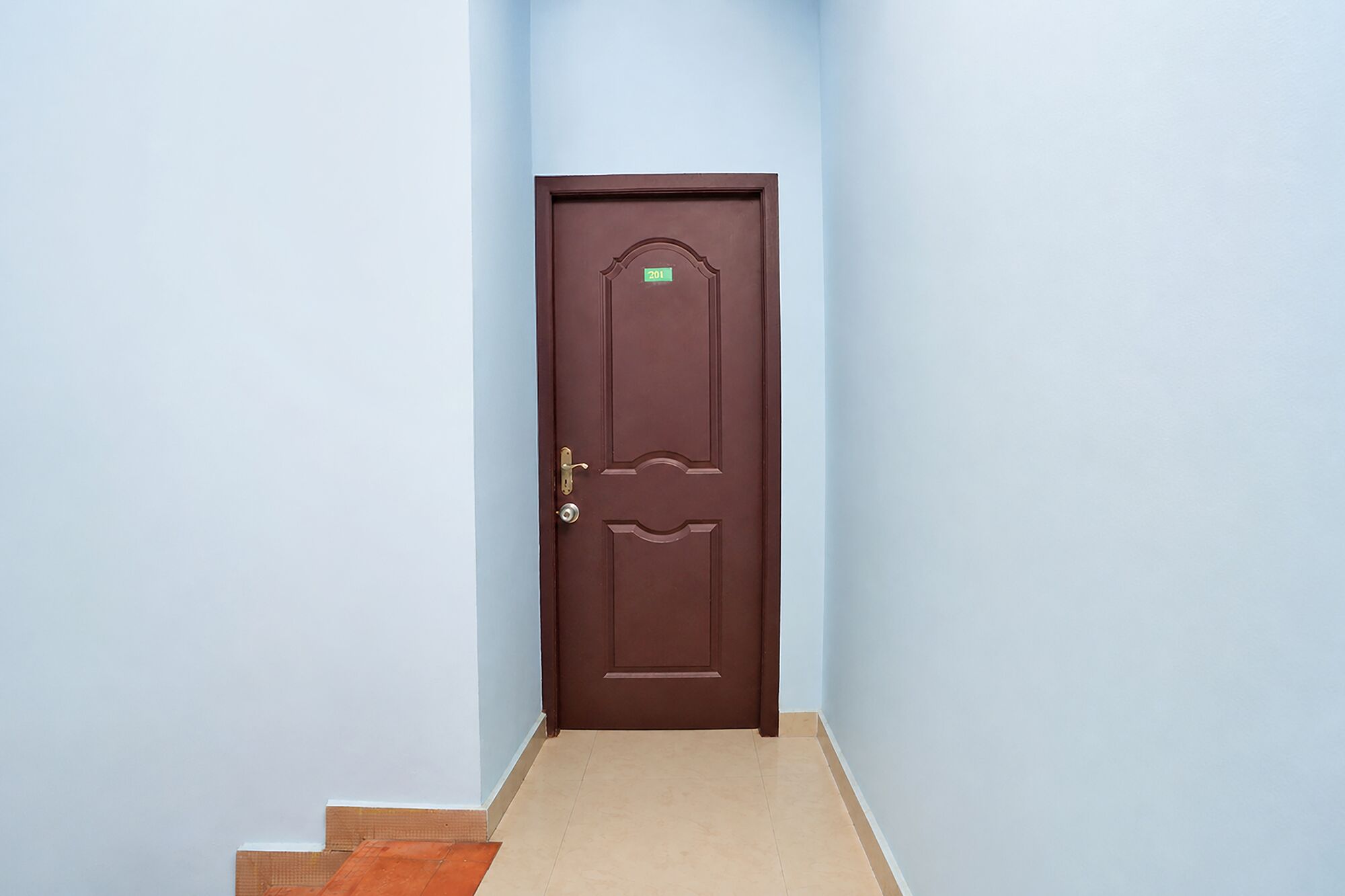 Puerta marrón cerrada con placa de identificación, picaporte y cerradura.