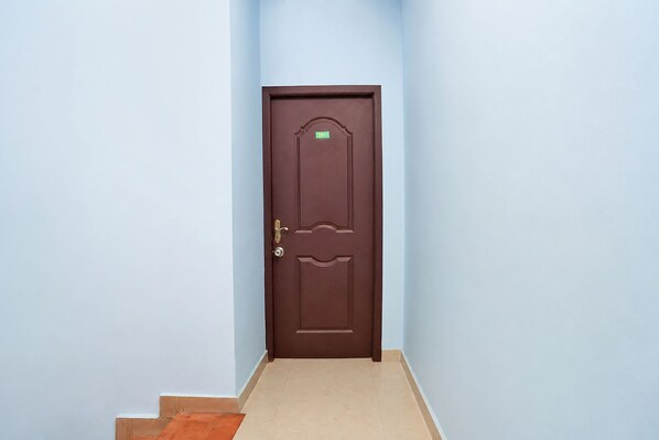A closed brown door with a number plate, a doorknob, and a lock.