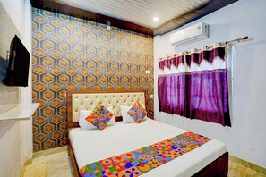 A hotel room with a bed, a patterned wall, a window with curtains, and an air conditioning unit. - FabHotel National Banaras Inn (Varanasi)