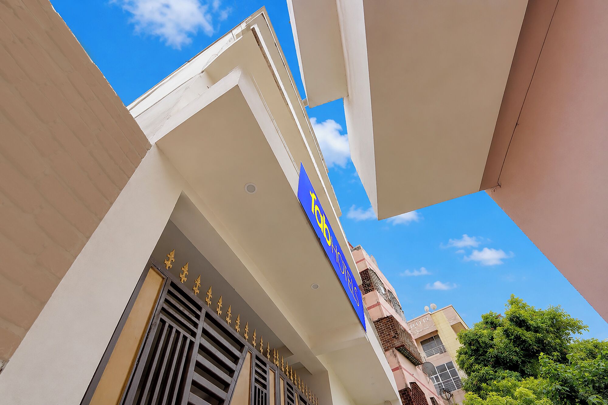 Un hotel con un cielo azul despejado al fondo, con un letrero azul destacado con letras doradas.