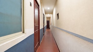 Ein schmaler Flur mit Türen an beiden Seiten, einer strukturierten Wand und einem gefliesten Boden.