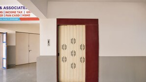 A hallway with a double door, a sign above indicating services, and a tiled floor. - Fabhotel Royal Midway (Gandhinagar)