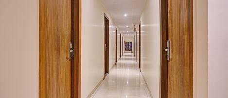 Un pasillo de hotel con puertas de madera y suelo de baldosas.