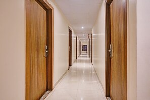 A hotel corridor with wooden doors and a tiled floor. - FabHotel Address Inn (Mumbai)