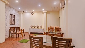 A dining area with a glass-top table, wooden chairs, and a white tablecloth. - Fabhotel Address Inn (Mumbai)