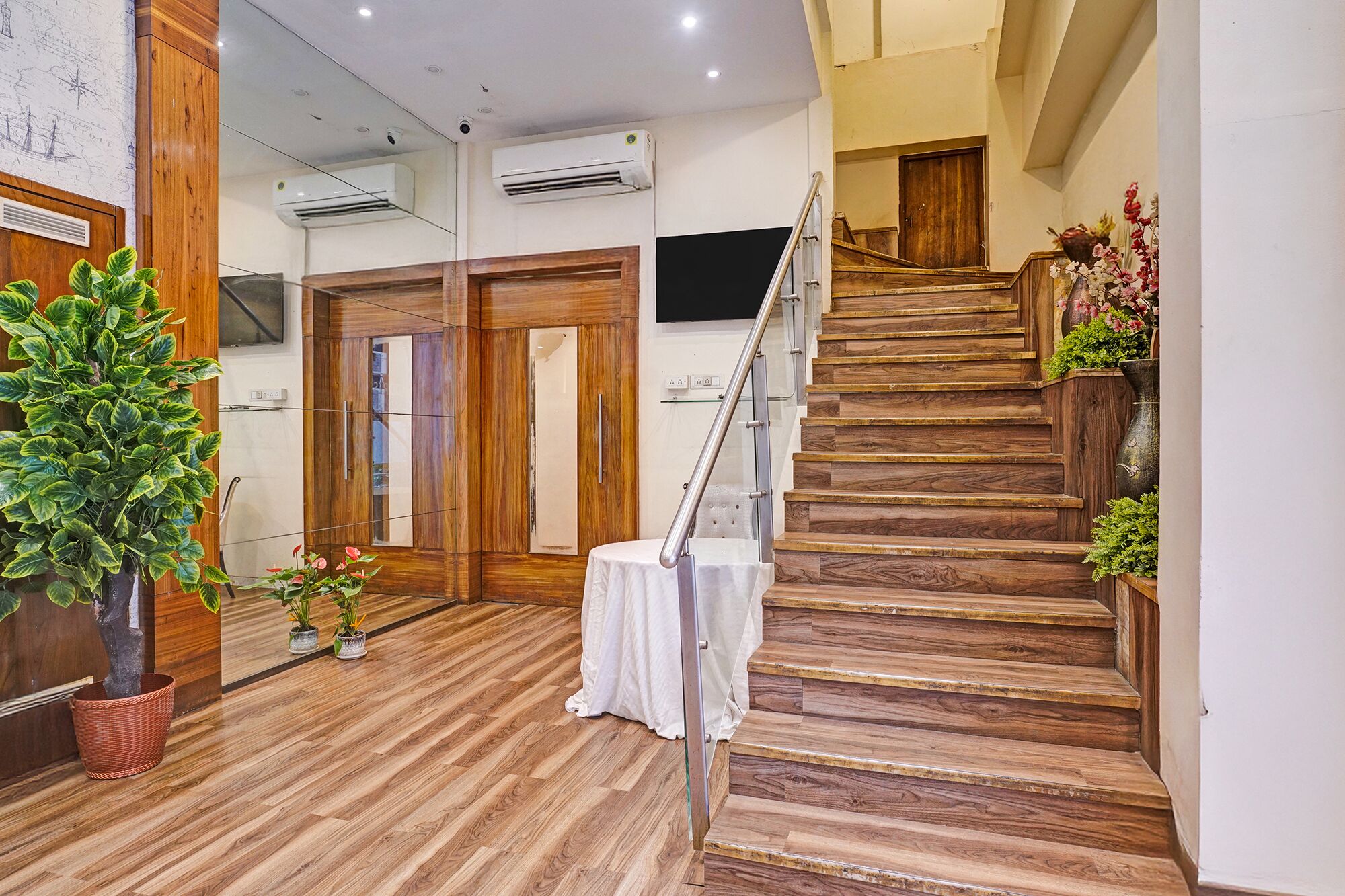 Una escalera de madera con barandilla metálica que conduce a una habitación con una mesa y sillas blancas.