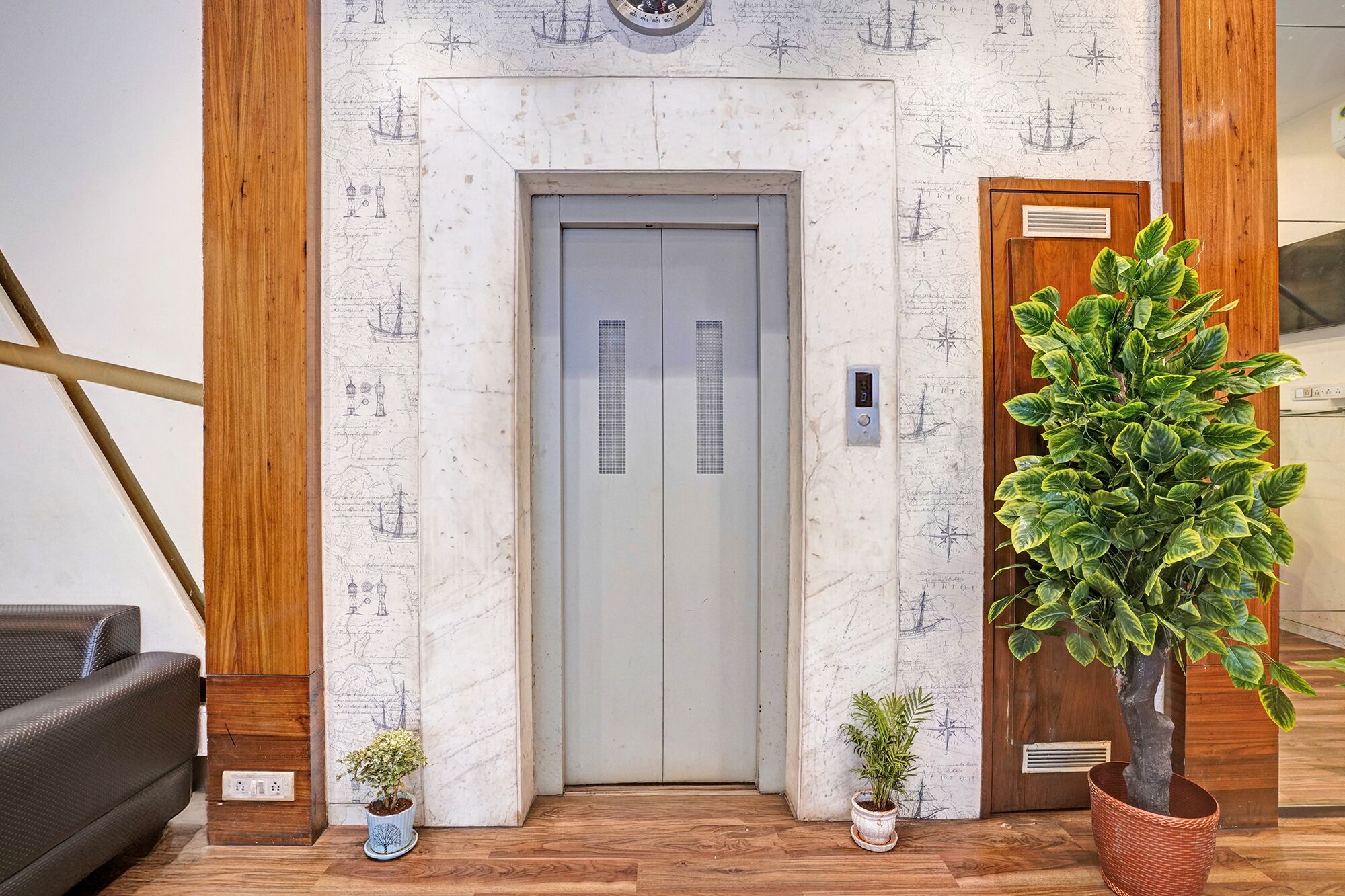 An elevator with a map wallpaper, a potted plant, and a wooden floor.