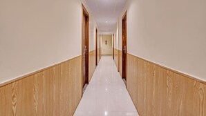 A long, narrow hallway with wooden paneling on the walls and a tiled floor. - Fabhotel Address Inn (Mumbai)