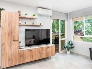 Ein modernes Wohnzimmer mit Flachbildfernseher, Holzschränken und einer eingebauten Klimaanlage.