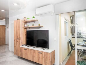 A modern living room with a flat-screen TV, wooden cabinet, and shelves with plants. - La Sirena by Interhome (Torremolinos)