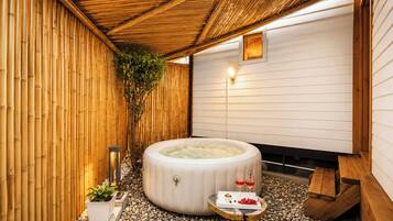 Un bain à remous situé dans un espace de détente, avec un mur en bambou et un plafond en bois.