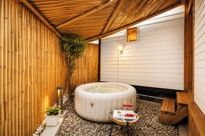 Een whirlpool in een spa-ruimte met een bamboevloer en een houten plafond.