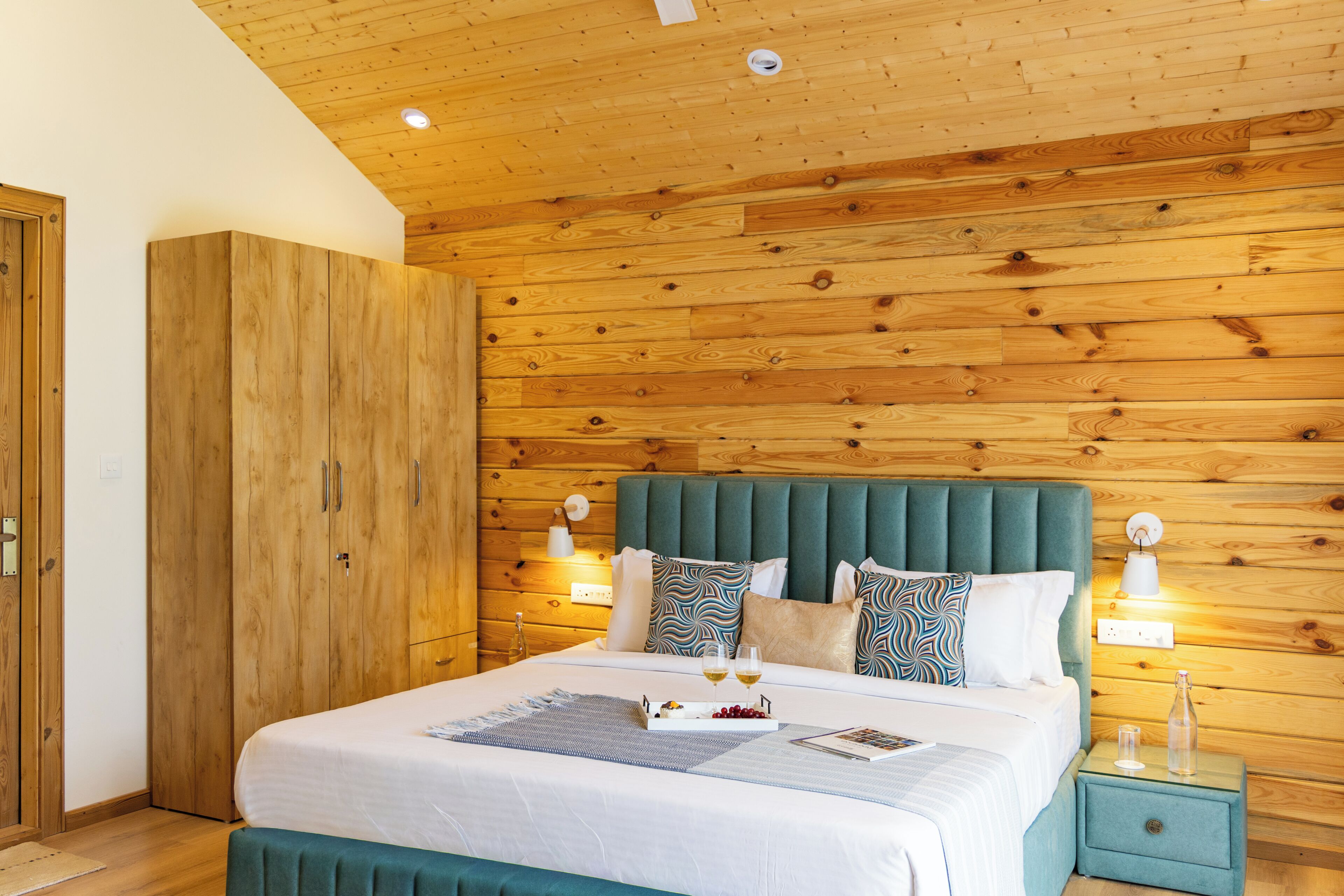 A bedroom with a wooden headboard, a bed with white bedding, two bedside tables, and a wardrobe.