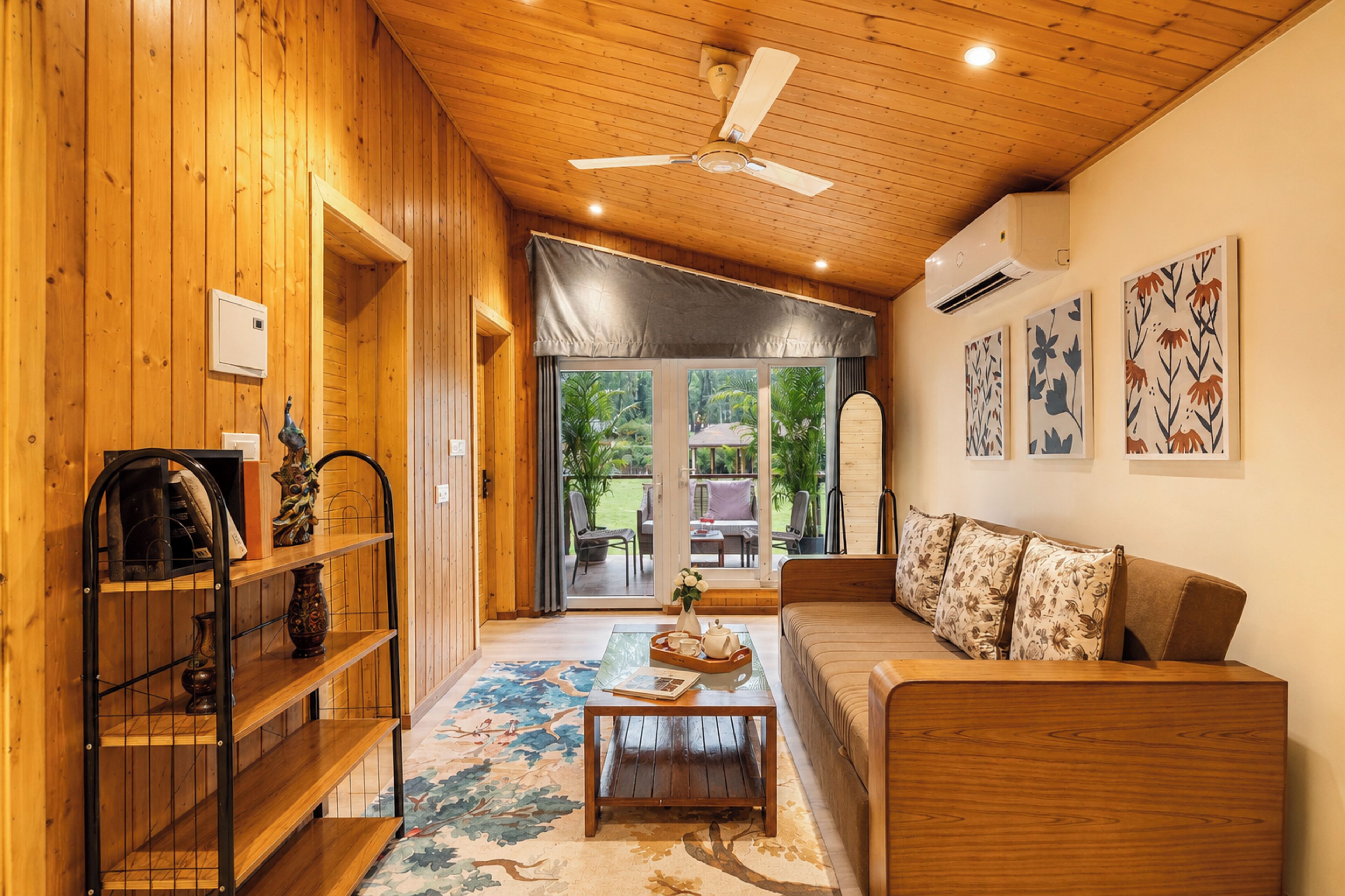 A wooden interior with a ceiling fan, a sofa, a coffee table, and a bookshelf.