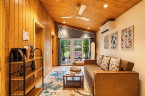 A wooden interior with a ceiling fan, a sofa, a coffee table, and a bookshelf. - Alaya stays Alora in the hills (Dehradun)