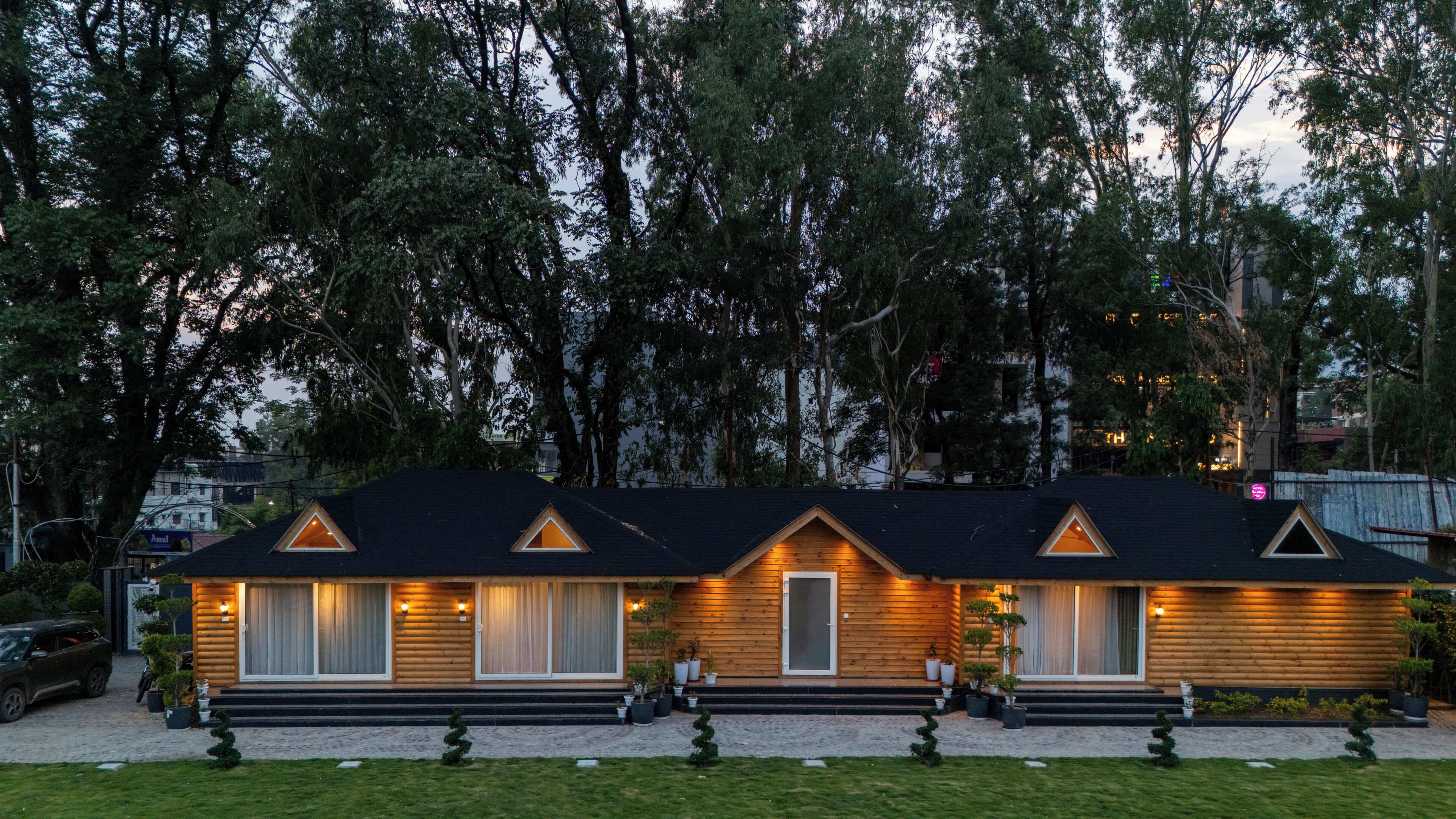 A row of log cabin-style buildings with multiple windows and a well-maintained lawn.