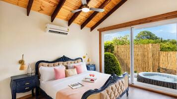A bedroom with a bed, bedside tables, a ceiling fan, and a view of a bamboo fence through a sliding glass door.