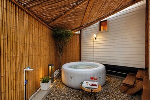 A spa area with a hot tub, a small table with drinks, and a bamboo wall. - Alaya stays Alora in the hills (Dehradun)