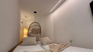 Un dormitorio con una cama, una silla colgante y una lámpara de noche.