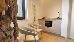 Una cocina moderna con armarios blancos, un grifo negro y suelo de madera.