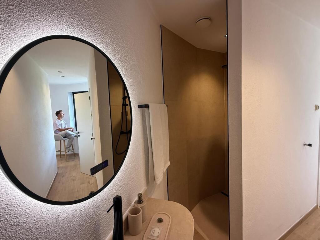 A bathroom with a mirror, a shower, and a toilet.