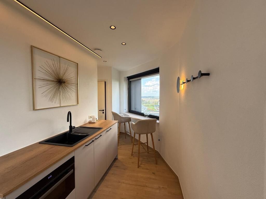 Una cucina moderna con un piano di lavoro in legno, un lavello nero e una finestra vista.