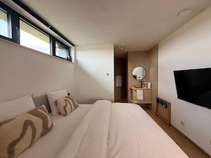 A hotel room with a bed, a TV, a mirror, and a window. - Water Tower Hotel WALDBADEN (Buetgenbach)