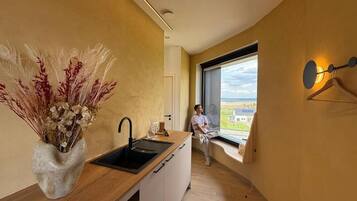 A modern kitchen with a large window, a sink, and a vase of dried plants.