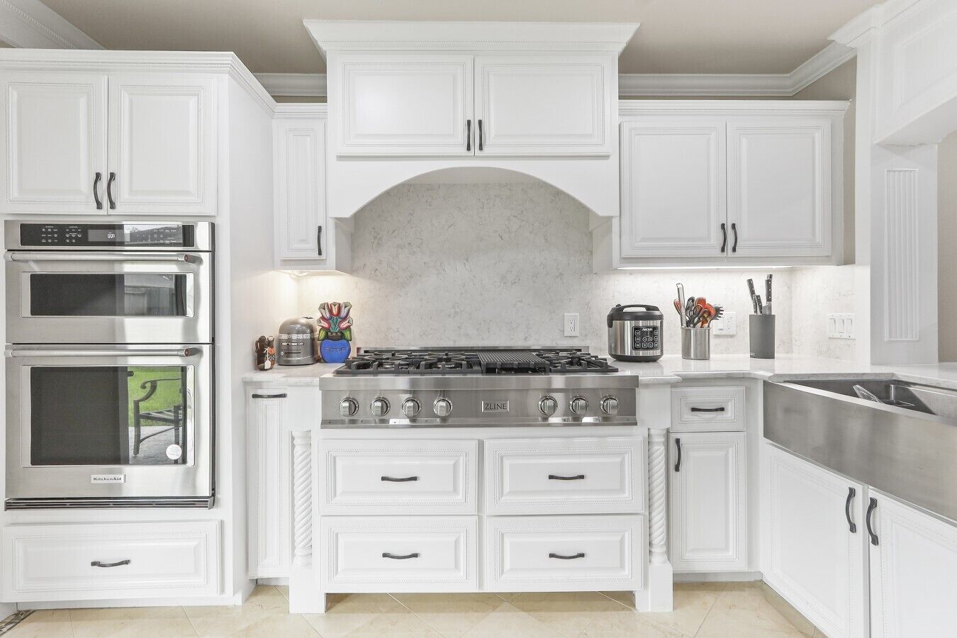 A kitchen with white cabinetry, a stainless steel stove, and a built-in oven.