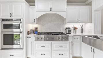A kitchen with white cabinetry, a stainless steel stove, and a built-in oven.