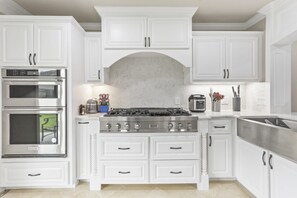 A kitchen with white cabinetry, a stainless steel stove, and a built-in oven.