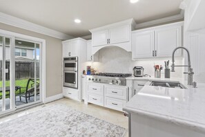 A kitchen with white cabinetry, a built-in oven, a stove, and a sink. - Sweet Home - Private Room in a Shared Home (Houston)