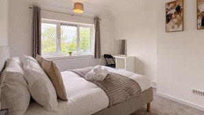 Une chambre à coucher comprenant un lit, une fenêtre, un bureau et deux œuvres d’art accrochées au mur.