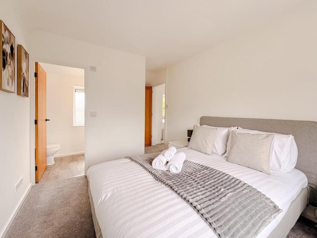 A hotel room with a large bed, a bedside table, and a view of the bathroom.